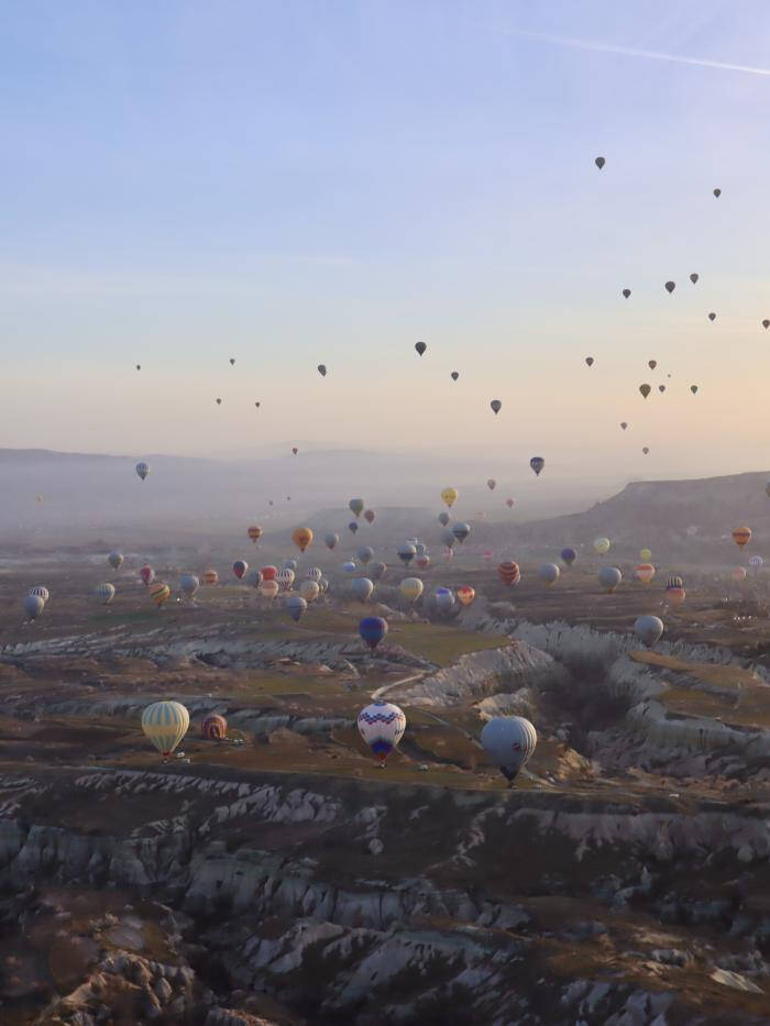 Photograph of hot air balloons floating over a landscape